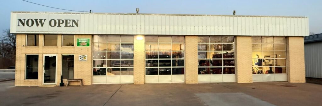 Front of auto shop. Building has 4 bays and a sign that reads, "Now Open"
